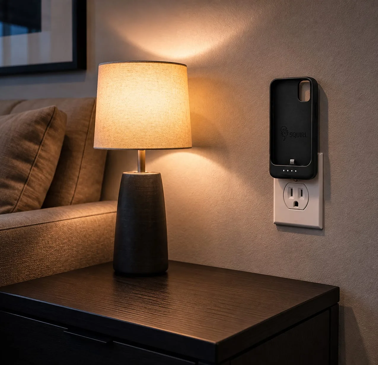 SQUIRL case plugged into a bedside wall outlet beside a lamp
